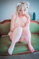 A woman sitting on a green couch wearing pink stockings.